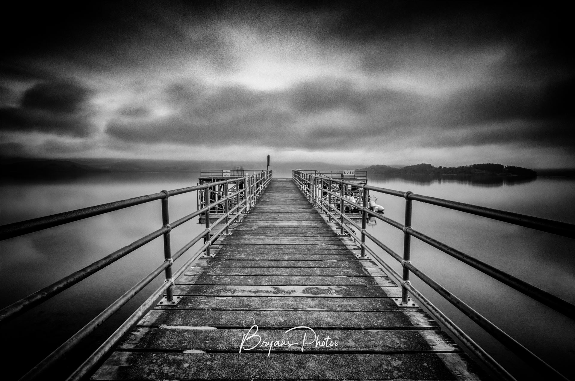 Luss Pier - A black and white long exposure photograph of Luss Pier on the banks of Loch Lomond. by Bryans Photos