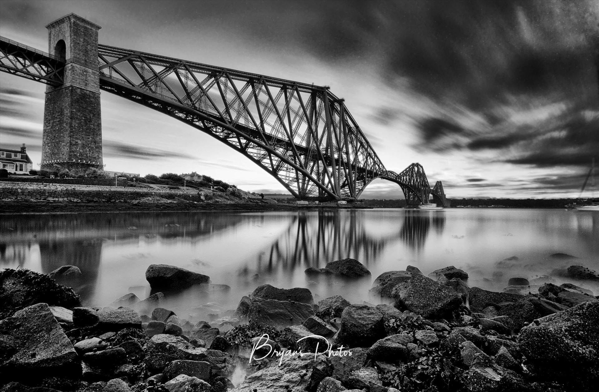 The Rail Bridge Black & White - A black and white long exposure photograph of the iconic Forth Rail Bridge taken on a summer evening from North Queensferry on the banks of the river Forth. by Bryans Photos