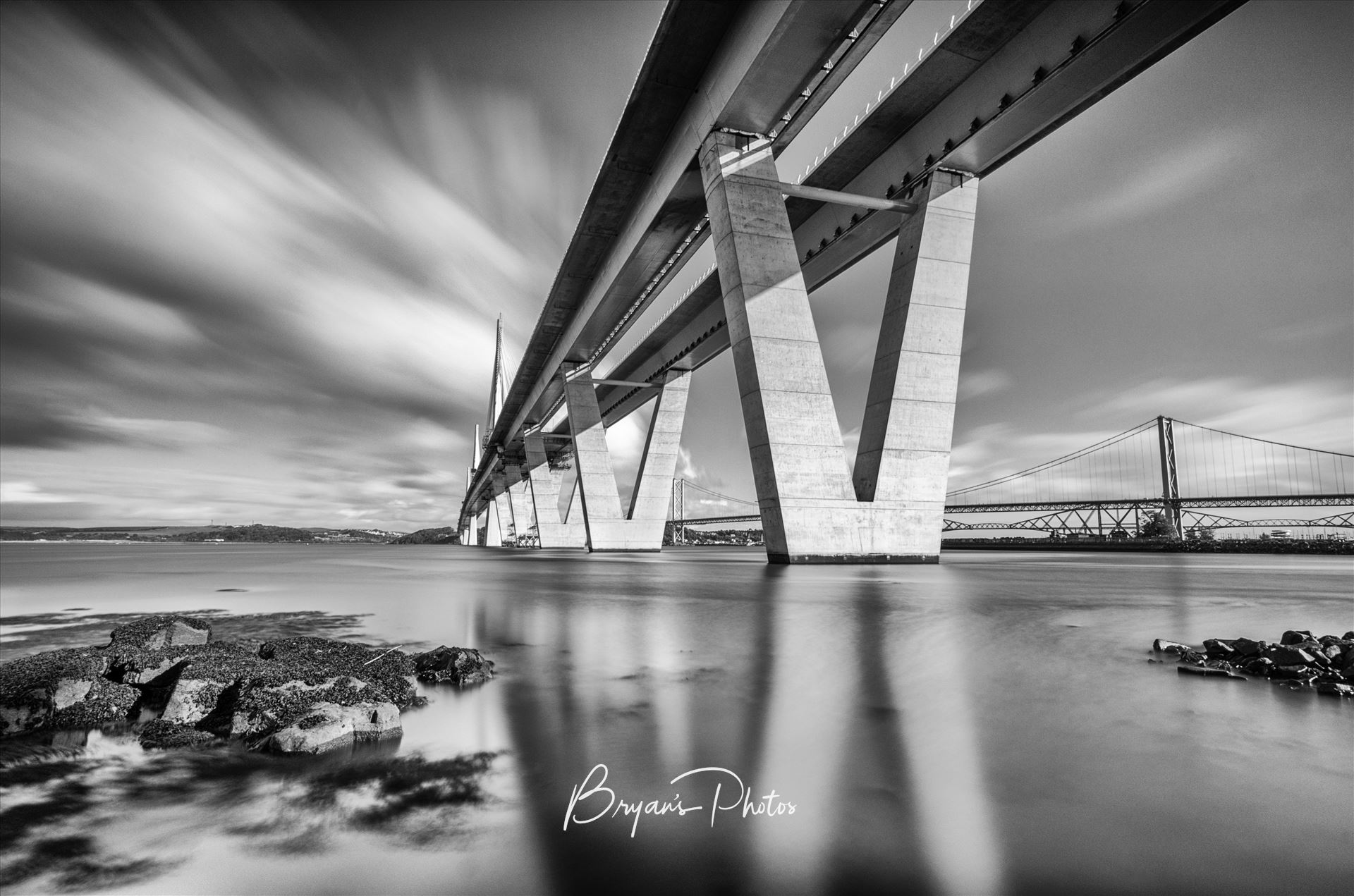 The Crossing - A black and white long exposure photograph of the Queensferry Crossing taken from the south bank of the river Forth at high tide. by Bryans Photos