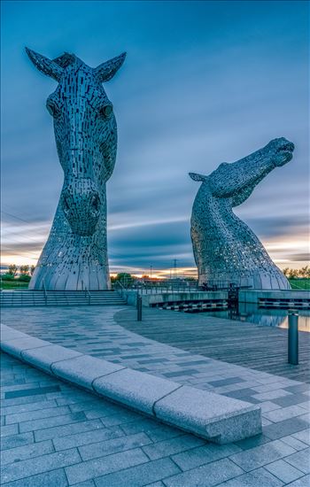 A long exposure photograph of the Kelpies taken just before sunset.