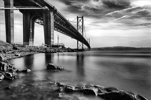 A daytime long exposure of the Forth Road Bridge taken from North Queensferry in black and white.