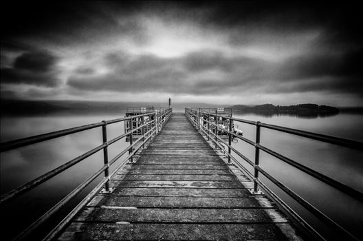 A black and white long exposure photograph of Luss Pier on the banks of Loch Lomond.