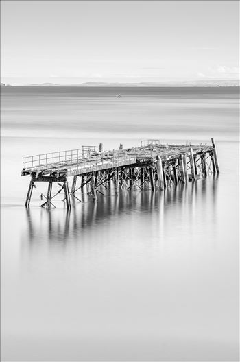 A black and white photograph of the remains of Carlingnose Pier on the Fife coast of Scotland.