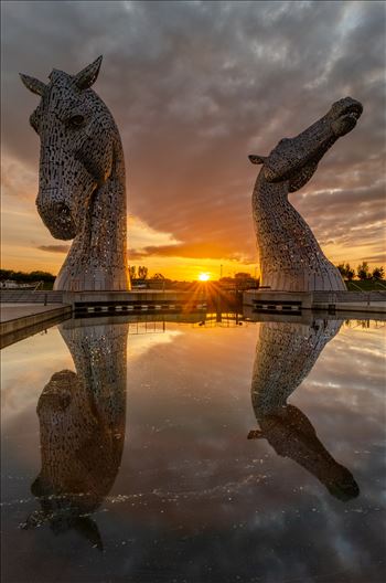 A photograph of the Kelpies taken as the sun sets in between them.